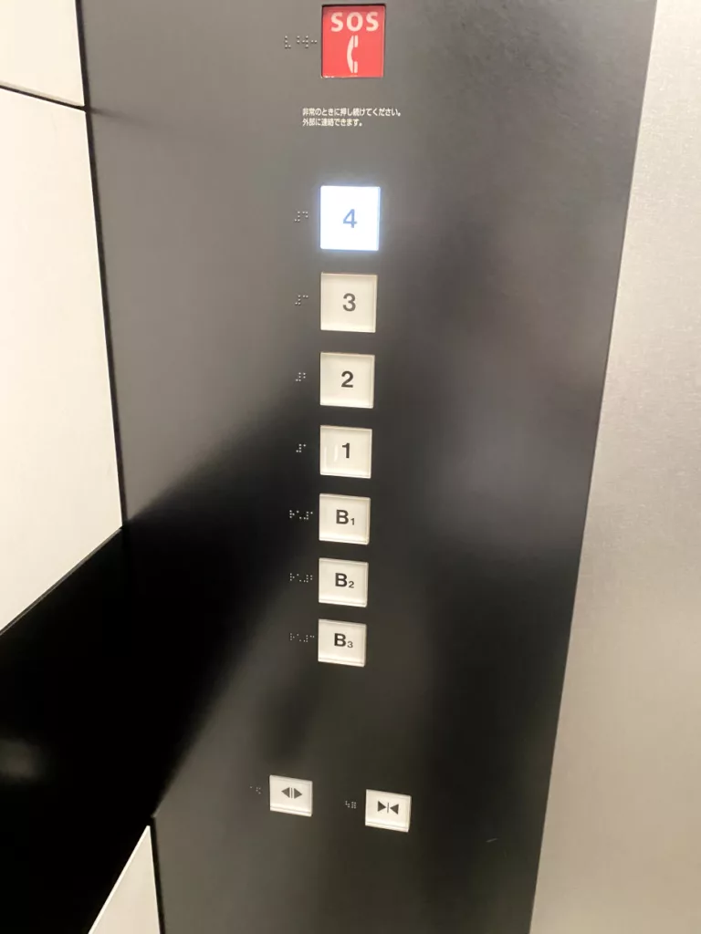 写真: エレベーターのフロア選択ボタンの横に点字が記載されている。