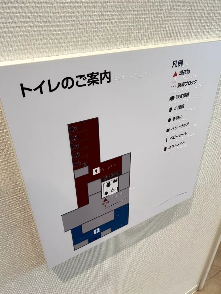 写真: トイレの案内に点字が記載されている。